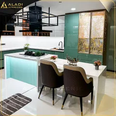 This modern kitchen is the heart of the home, featuring a mint-green island with an integrated cooktop and a breakfast bar. The design combines functionality with style, including a custom overhead rack for storage and display, and high-end quilted dining chairs.