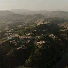 An even wider establishing shot of the ITC property in Udaipur, showing the resort complex in the context of the surrounding hills and nearby lake. This type of large scale aerial photography is essential for showcasing the location's exclusivity and scale.