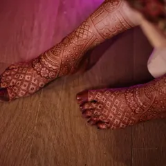 A close up of a bridal foot design, showing the rich, dark stain of my organic henna against the wooden floor. The design is intricate and covers the entire foot.