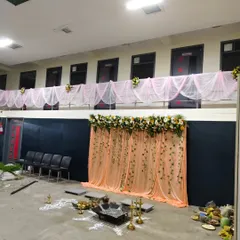 A wider view of the anniversary celebration hall, showing the main stage backdrop and coordinating fabric draping along the upper balcony for a complete, unified look.