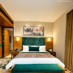 This is our deluxe room, featuring a plush, king-sized bed with an elegant emerald green headboard. It’s a space designed for deep rest and rejuvenation after a day in the city.