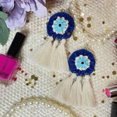 My popular Evil Eye macrame earrings, designed to be both a stylish accessory and a symbol of protection. This close-up shows the detailed knotting in concentric circles of blue, white, and turquoise, finished with three delicate off-white tassels.