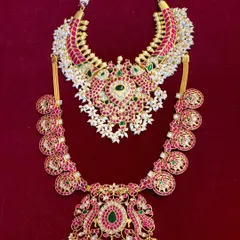 This is a stunning bridal combo set featuring a Jadua Kundan choker and a matching long haram. The pearl accents add a touch of softness to the bold design.