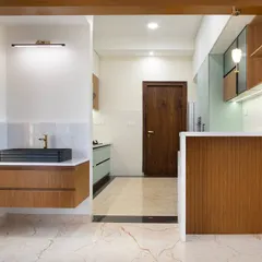 This view shows the kitchen's connection to the rest of the home, with a wooden breakfast bar that adds warmth and a casual dining spot. The floating vanity outside is a unique, functional touch.