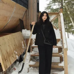 Ready for cabin life with a shovel in hand, wearing a practical but stylish winter outfit.