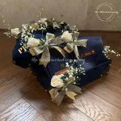 A closer look at our beautifully decorated travel hamper. The personalized cap, passport cover, and other accessories are individually wrapped with delicate ribbons and flowers for a luxurious unboxing experience.