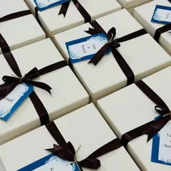 A collection of elegantly wrapped gift boxes for the wedding party. Each box is finished with a rich brown ribbon and a custom tag with the guests' names.