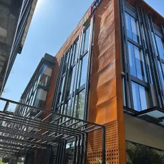A low-angle shot of the Sattva Auro commercial building, emphasizing the verticality of the glass and steel elements against the corten steel cladding.