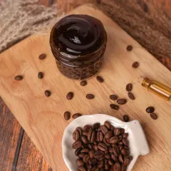 A DIY coffee scrub styled on a wooden board with coffee beans. The rustic and earthy tones perfectly match the product's main ingredient.