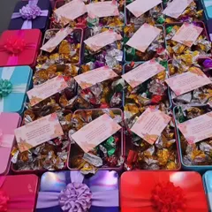 A colorful array of budget-friendly chocolate boxes for a birthday party. Each tin is filled with assorted chocolates and includes a personalized thank you card.
