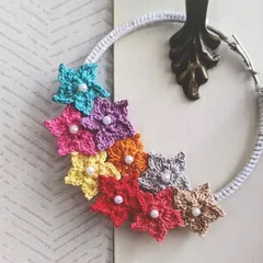 A close-up of the floral hoop, showing the detail of each tiny crocheted flower, complete with a pearl-like bead in the center. We can customize the flower colors for you.