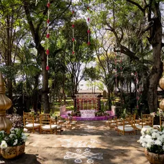 An outdoor wedding ceremony set amidst nature. I designed the aisle with traditional rangoli patterns leading to the mandap, ensuring the entire space felt like a serene, open-air temple for the couple's union.