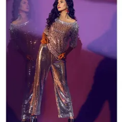A full-length shot of a model in a retro-glam party outfit, featuring a silver sequin boatneck top and matching wide-leg sequin trousers.