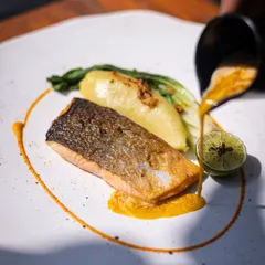 A beautifully cooked piece of salmon, with crispy skin and moist flesh, served over carrot puree and mashed potato with a saffron beurre blanc.