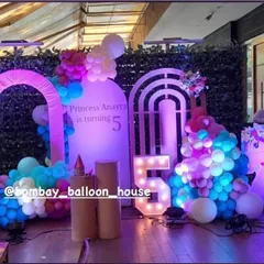 A magical unicorn-themed party setup with illuminated unicorn props, pastel balloon arrangements, and a light-up number "5".