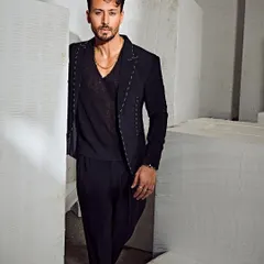 Tiger Shroff in a sleek, all-black Tisa Studio suit. The subtle white stitch detailing on the blazer adds a modern, deconstructed touch to this powerful look.