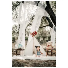 A sweet and serene portrait of a little girl enjoying her first birthday picnic. The teepee and teddy bears create a magical, storybook setting.