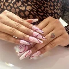 Long and elegant coffin-shaped nails with a beautiful design featuring abstract purple and white swirls.