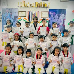 A full class of students proudly displaying their new yellow and green belts and certificates. This is a testament to their hard work and the guidance of their coaches.