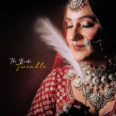A soft and serene bridal portrait. The bride's gentle touch with the feather and her peaceful expression create a dreamy and timeless image, highlighting her stunning jewelry and makeup.