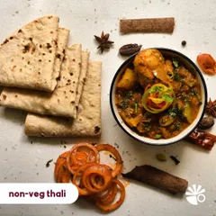For my non-veg lovers, this thali is for you. It features a hearty chicken curry, prepared with whole spices, served alongside soft rotis and tangy pickled onions. A truly satisfying meal.