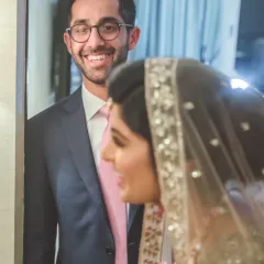 A candid shot capturing the groom's happy expression as he sees his bride. These "first look" moments are filled with genuine emotion and make for unforgettable photos.