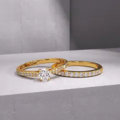 A timeless pairing for a timeless commitment. This custom bridal set includes a classic solitaire diamond engagement ring and a matching diamond eternity band, both crafted in radiant 18k gold. The beauty is in its elegant simplicity and flawless sparkle.