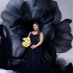 A classic black gown paired with a dramatic black flower backdrop for a touch of modern elegance. The pop of yellow from the flowers adds a beautiful, hopeful contrast.