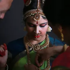 Another close-up of the getting-ready moments, as family helps adjust the intricate costume and jewelry for the Bharatanatyam performance.