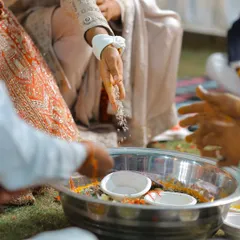A close-up detail shot of the rituals being performed, focusing on the hands and the offerings.
