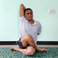 Gomukhasana (Cow Face Pose), front view. This seated pose deeply stretches the hips, shoulders, and chest. The challenge is to keep the spine erect and the shoulders back.