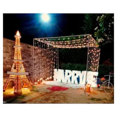 This is my signature grand proposal setup, arranged in a garden at night for maximum impact. It features large, illuminated 'MARRY ME' letters under a canopy of draped fairy lights, with rose petals on the ground to create a truly romantic pathway.