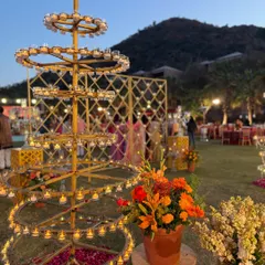 A traditional tiered diya stand, or 'deepamala', becomes a stunning centerpiece for an outdoor evening event in Udaipur.