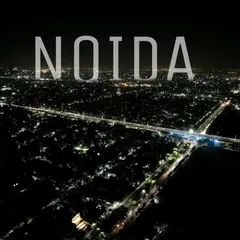 A nighttime aerial view of Noida, capturing the bright lights of the city's roads and infrastructure.