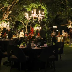 An outdoor seating area for a monochrome-themed event. We brought the elegance outdoors with black velvet chairs and crystal chandeliers hanging from the trees, blending nature with refined luxury.