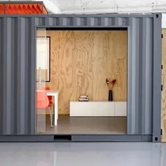 The exterior of a container transformed into a sleek, contemporary office. The industrial strength of the container is paired with refined design elements like a large sliding glass entryway, creating a professional and inviting workspace.