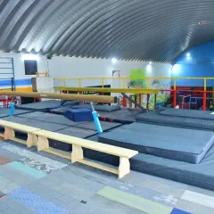 This angle shows our setup with multiple balance beams, thick safety mats, and benches. We have all the necessary equipment for comprehensive gymnastics training.