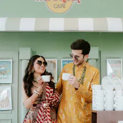 A quirky and cute moment of the couple enjoying a cup of chai at a Hard Rock Cafe themed setup during their haldi event in Jaipur.