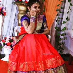 A client ready for her ring ceremony in a vibrant red and blue half saree. Her makeup is bright and celebratory, with henna-adorned hands completing the look.