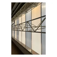 The interior of the industrial building reveals the steel truss structure and translucent wall panels. This system allows diffused natural light to illuminate the workspace, reducing the need for artificial lighting.