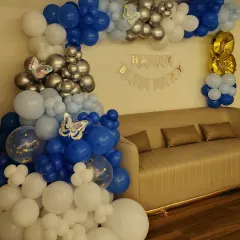 A butterfly-themed balloon arch in shades of blue, white, and silver, perfect for a sophisticated birthday celebration at home.