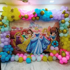 A grand Disney Princess theme featuring a large backdrop with Cinderella, Belle, Rapunzel, and Snow White. The scene is framed by a vibrant, multi-colored balloon arch.