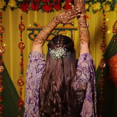 A creative pose showing off the intricate mehndi design and a beautiful bridal braid.