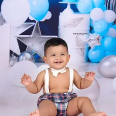 A joyful moment from a cake smash session, with the birthday boy laughing happily. The blue and silver star-themed background adds a festive touch to this celebratory portrait.