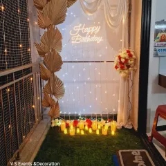 I can turn even a small balcony into a romantic spot for a birthday surprise. This setup includes a fairy light curtain, a neon sign, elegant drapes, and floral details.