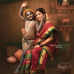 A cheerful wave from little Krishna in this beautifully styled studio session. The earthy tones of the backdrop and traditional props like clay pots create an authentic setting, making the portrait feel like a scene from a classic story.