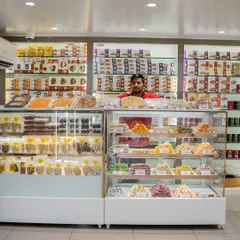 Welcome to my shop. I believe in serving you with a smile and helping you find exactly what you need. Behind this counter, you'll find everything from daily snacks to special sweets for big occasions, all fresh and ready.
