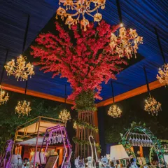 A bar should be more than just a place for drinks; it should be a centerpiece. This stunning bar setup features a magnificent red floral tree under a canopy of glowing chandeliers, making it a true 'Headquarters of Drinks'. 🥂