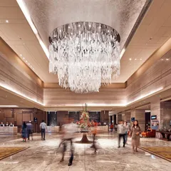 A wide-angle view of the bustling Sheraton lobby. The combination of marble flooring, warm ambient lighting, and the central light sculpture creates a space that feels both grand and welcoming to guests.