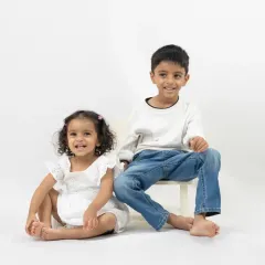 A mother and her children share a playful, loving moment against a clean, white background. This minimalist style allows their genuine emotions to be the focus of the photograph.